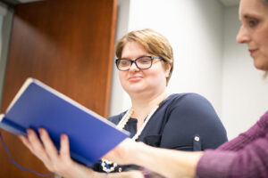 Two people looking at a notebook in an office.